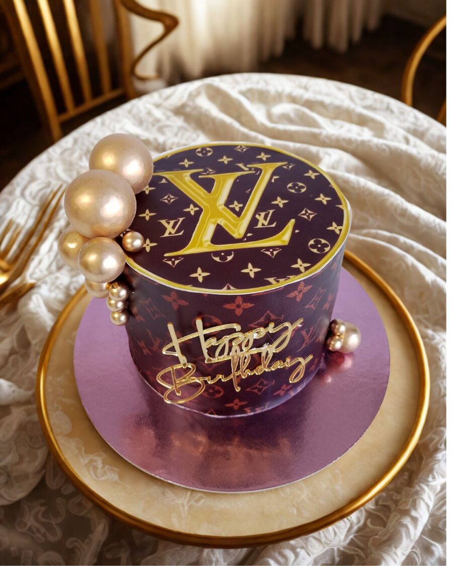 Bolo Louis Vuitton com padrão icónico e pérolas douradas, disponível por encomenda com 72h de antecedência.