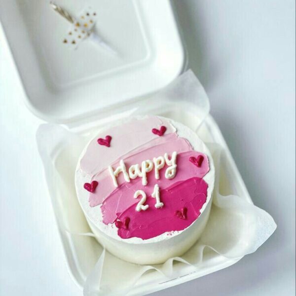 Mini bolo rosa decorado com corações e lettering “Happy 21”.