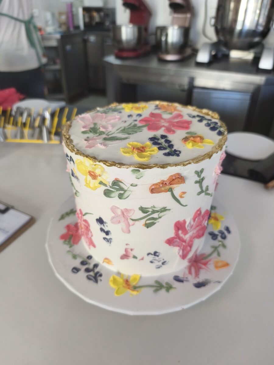 Bolo floral com flores pintadas à mão e borda dourada em buttercream.