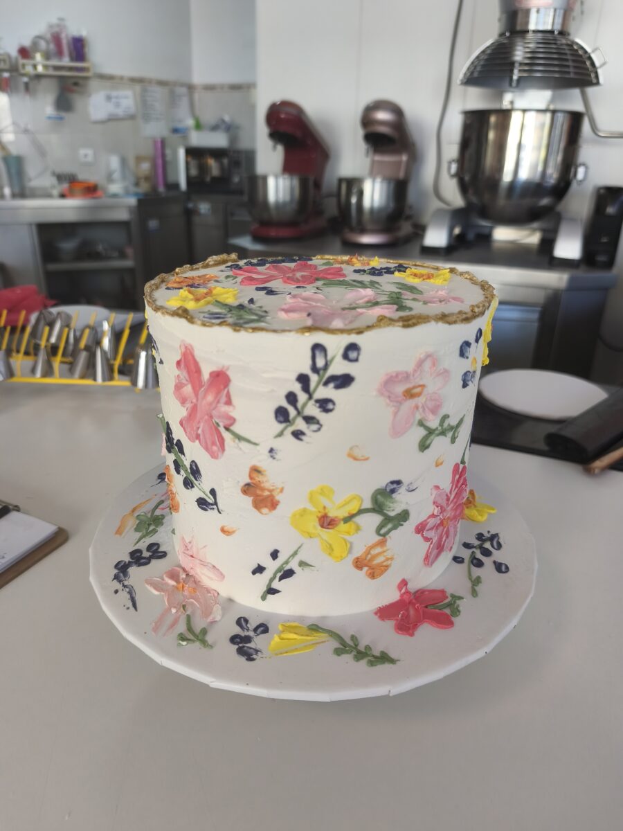 Bolo floral com flores pintadas à mão e borda dourada em buttercream.