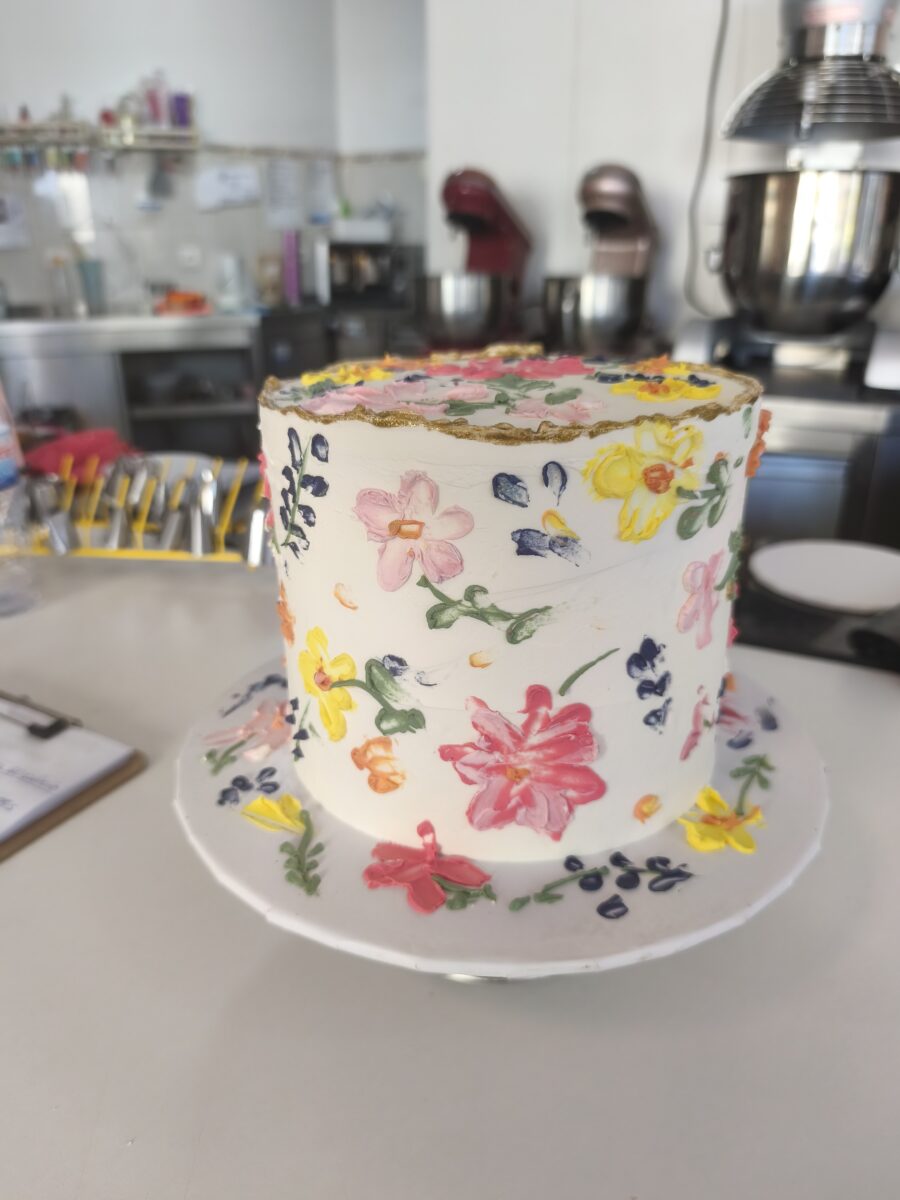 Bolo floral com flores pintadas à mão e borda dourada em buttercream.