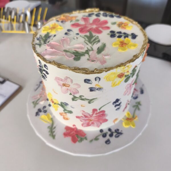 Bolo floral com flores pintadas à mão e borda dourada em buttercream.