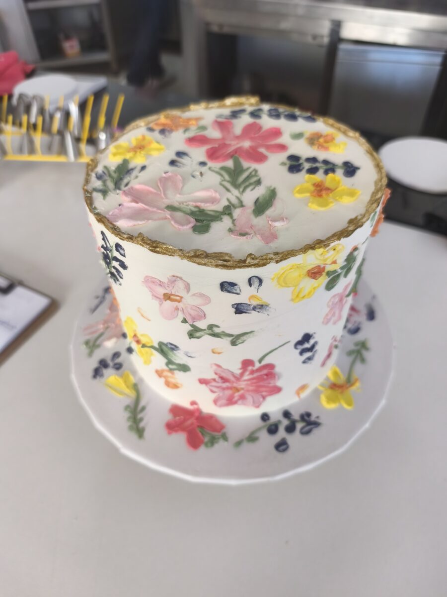Bolo floral com flores pintadas à mão e borda dourada em buttercream.