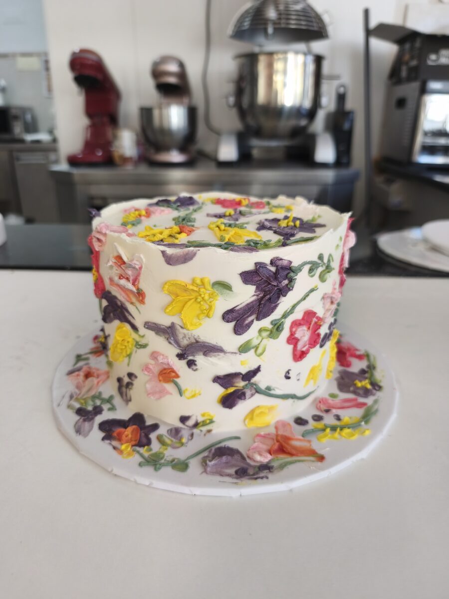 Bolo floral pintado à mão com buttercream colorido em tons vibrantes.