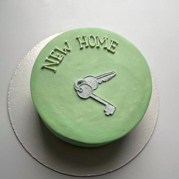 Mini bolo verde com decoração “New Home” e chave prateada.